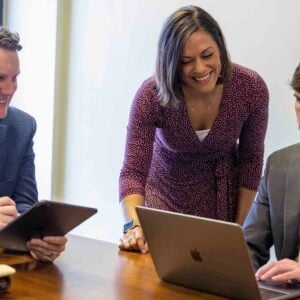 Workers gathered around a laptop in a conference room