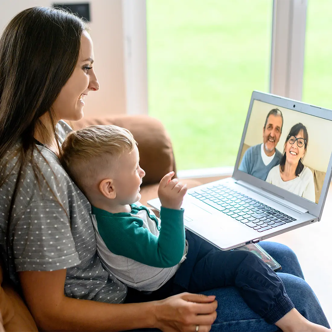 Mother and son video chatting with grandparents on laptop