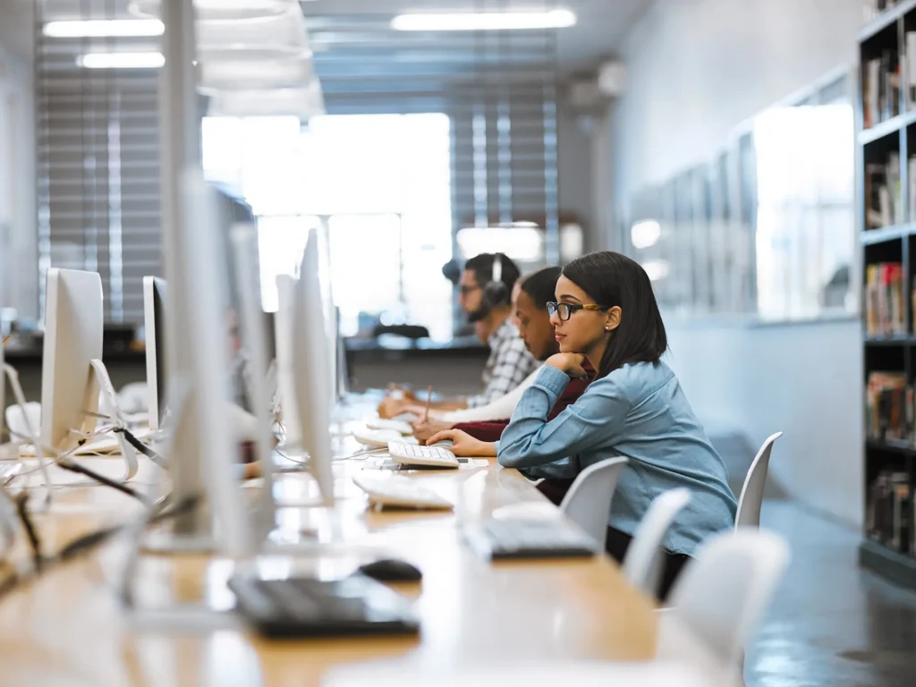 People at desktops on long a long table
